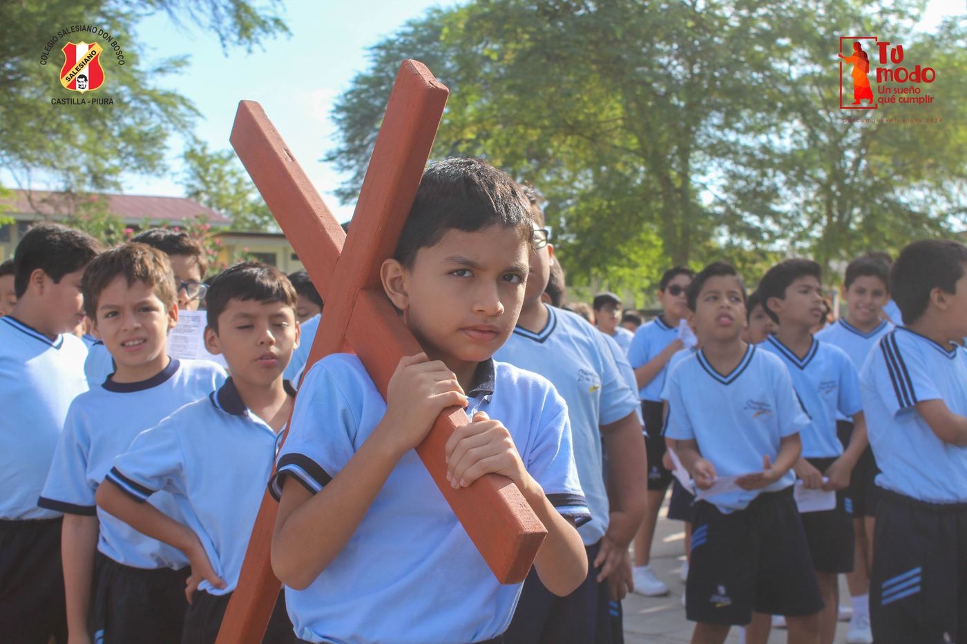 Estudiante cargando la cruz en el Viacrucis